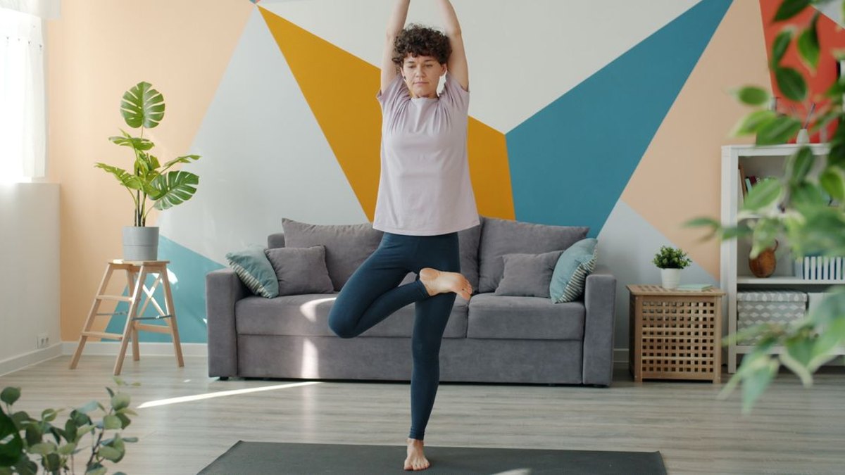 경도 단계에서는 무엇부터 시작하면 될까요? — 경도 단계는 진단은 받았지만 걷는 데 큰 지장이 없는 상태입니다. 이 단계의 핵심은 증상을 악화시키는 자세를 피하고 굴곡 위주… · 사진: Adult woman doing yoga in a modern, colorful living room with geometric wal…